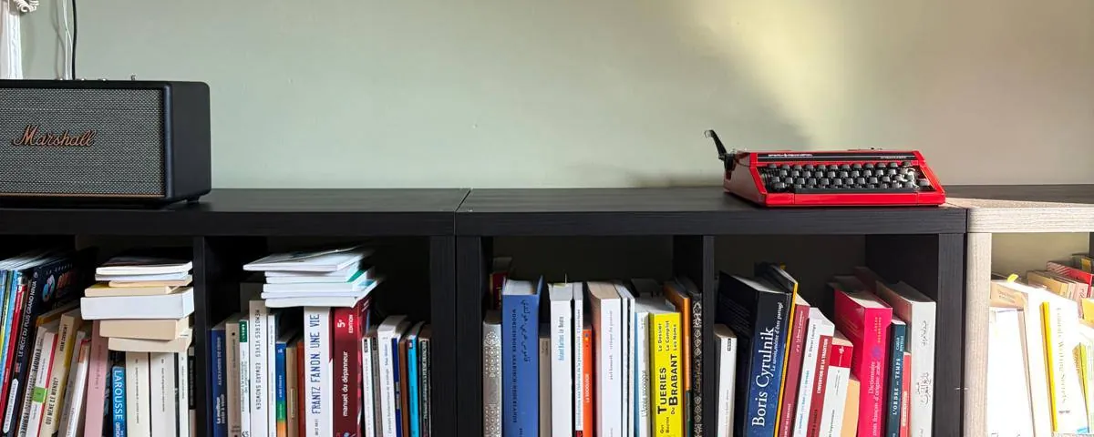 Une machine à écrire rouge posée sur une bibliothèque remplie de livres